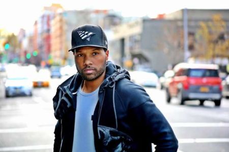 Mendeecees Harris in a black jacket and black cap poses for a picture.
